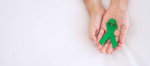Man holding green Ribbon for supporting people living and illness. Liver, Gallbladders bile duct, kidney Cancer and Lymphoma Awareness month concept Man holding green Ribbon for supporting people living and illness. Liver, Gallbladders bile duct, kidney Cancer and Lymphoma Awareness month concept lymphoma photos stock pictures, royalty-free photos & images