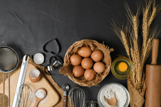 istock fresh eggs and cake flour  with kitchen utensils for pastries on black table, 1269694337