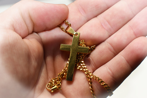Cruz de Oro Jesucristo en la palma de las manos de cerca de alta calidad photo