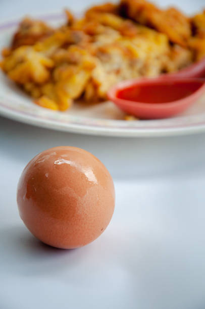 Whole raw brown chicken eggs with omelet background. Close up