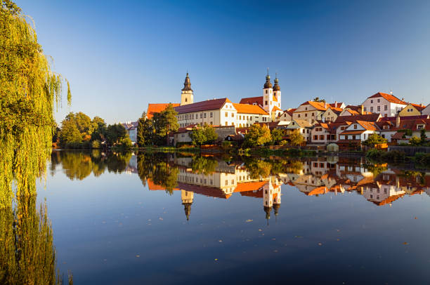 View of Telc with reflections in pond and willow on foreground in autumn, southern Moravia, Czech Republic.