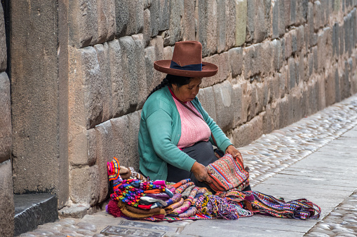 Cusco, Peru - october 08, 2018: Quechua women in traditional indigenous clothing selling colorful textile making local craft souvenirs