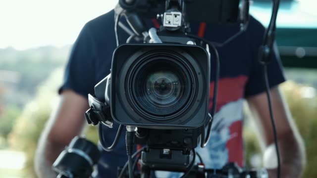 The cameraman zooms and focus with his camera on the TV broadcast. Film and television industry