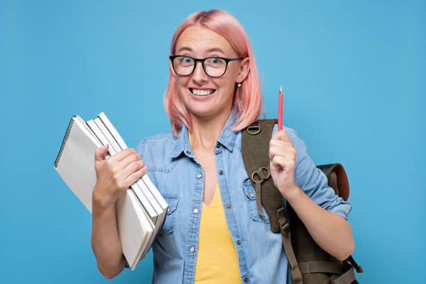 istock Caucasian young woman with books pointing up having idea. 1269707574