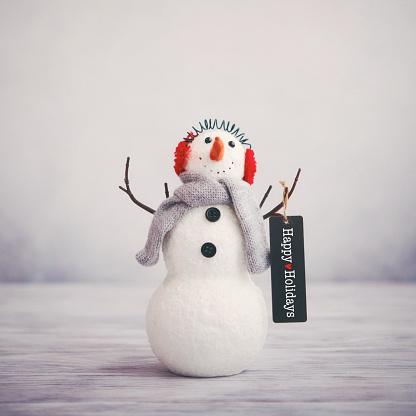 Bodegón de Navidad con lindo muñeco de nieve sosteniendo felicitaciones felices vacaciones photo