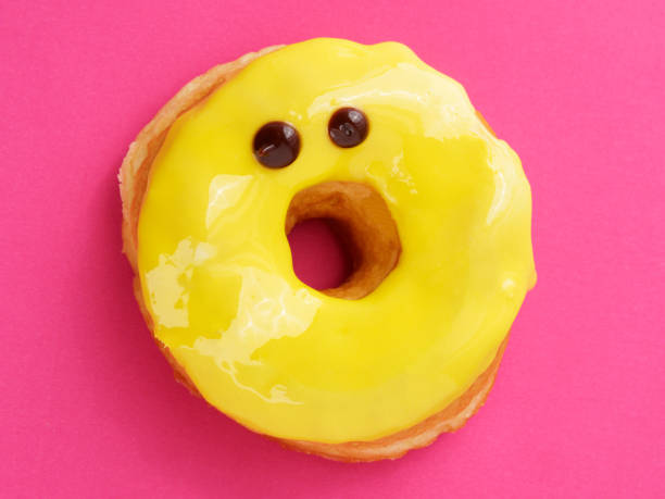 istock Funny yellow donut with eyes on a pink background. 1269708441