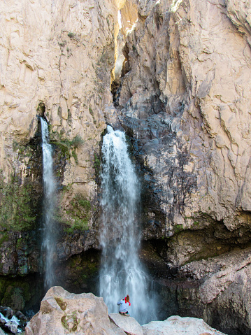 Girl taking pictures under a waterfall