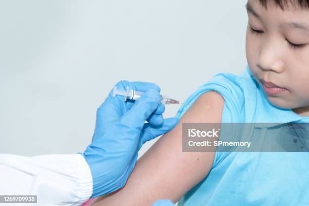 The Doctor Is Using A Syringe To Vaccinate The Asian Childs Shoulder In Hospital Virus Protection With Vaccination Concept Stock Photo - Download Image Now
