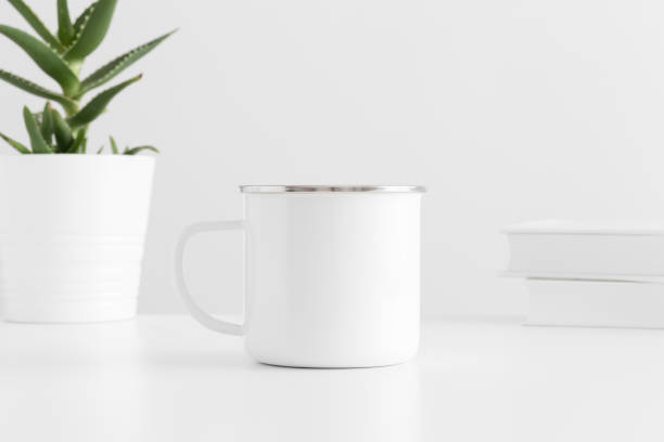 istock Enamel mug mockup with a aloe vera in a pot and books on a white table. 1269714008