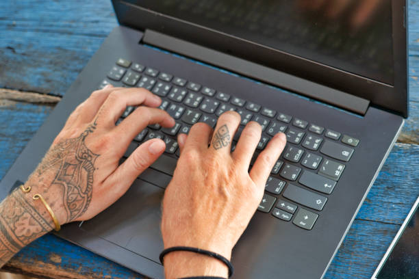 istock Womans tattoo hands typing on computer laptop close-up 1269714049