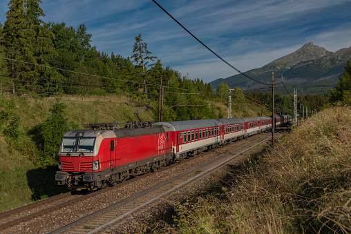 Red fast passenger train on main railway in Slovakia near Vysoke Tatry national park