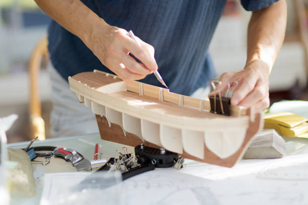 Asian man retirement hobby of wooden model ship building.