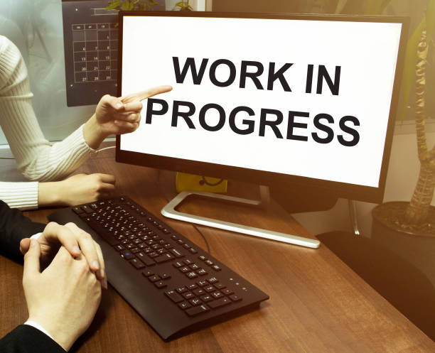 istock male and female hand, computer with text Work In Progress with office background 1269717589