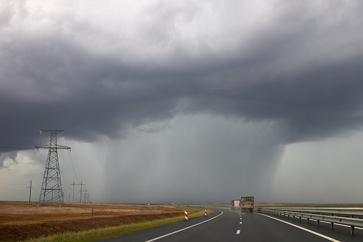 Heavy rain pours from a cloud hanging over the highway