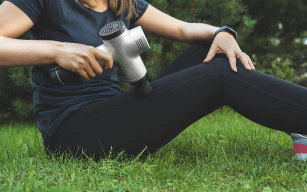 frau massieren bein mit massage percussion-gerät nach dem training. - physical therapy exercise machine exercising exercise equipment stock-fotos und bilder