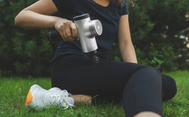 frau massieren bein mit massage percussion-gerät nach dem training. - physical therapy exercise machine exercising exercise equipment stock-fotos und bilder