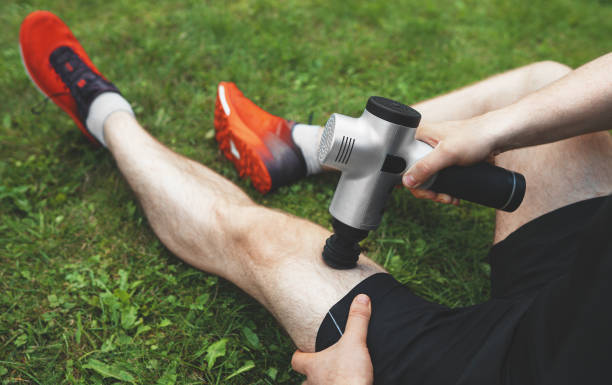 Man massaging leg with massage percussion device after workout.
