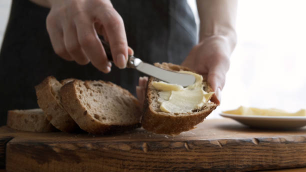 Spreading butter on bread Spreading butter on bread. Woman's hands making sandwich with bread and butter bun bread stock pictures, royalty-free photos & images