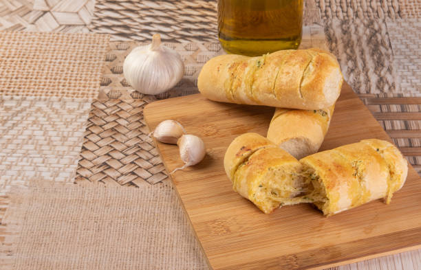 istock Garlic bread stuffed with cheese arranged on a cutting board with garlic around it and a bottle of olive oil on a table, selective focus. 1269730945