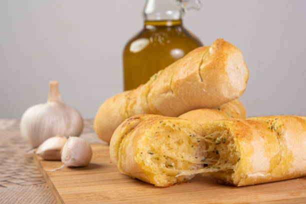 istock Garlic bread stuffed with cheese arranged on a cutting board with garlic around it and a bottle of olive oil on a table, selective focus. 1269730973