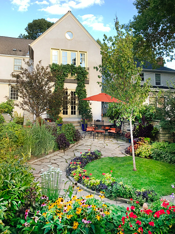 A residential home exterior. Backyard outdoor space with garden and patio.