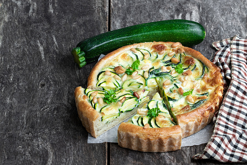 Vegetarian  pie with zucchini and pine nuts on rustic wooden table