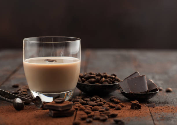 vidro de creme irlandês com grãos de café e pó com chocolate escuro no fundo de madeira escura. - cream liqueur - fotografias e filmes do acervo