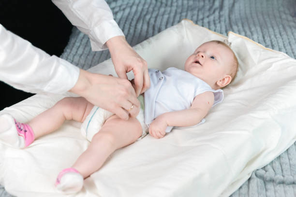 istock Mom changes the babys diaper. The baby is lying on the changing table and smiling 1269744197