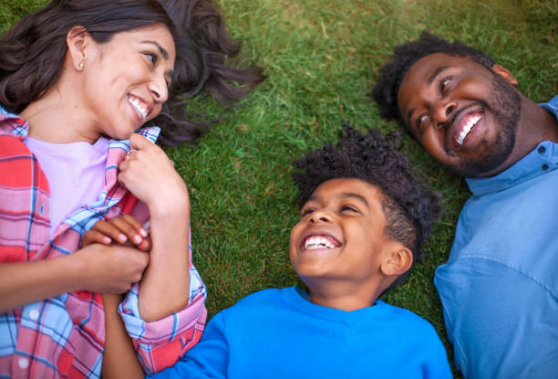 istock Multicultural mixed race multi-ethnic family with one child laying on grass laughing 1269747825