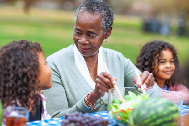 Grandmother with two granddaughters at picnic in park Grandmother with two granddaughters at picnic in park black people eating stock pictures, royalty-free photos & images