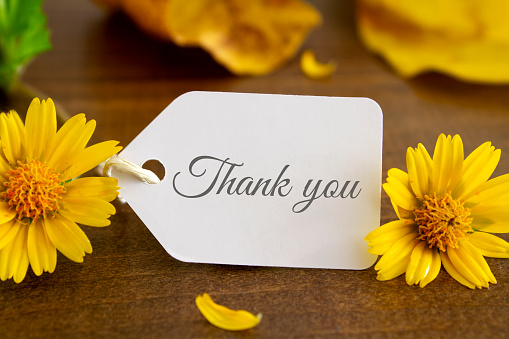 A hand written thank you note with cheerful yellow flowers.