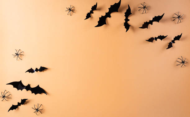 istock Halloween decorations made from paper bats and black spider on pastel orange background. Flat lay, top view with copy space for text. 1269750993