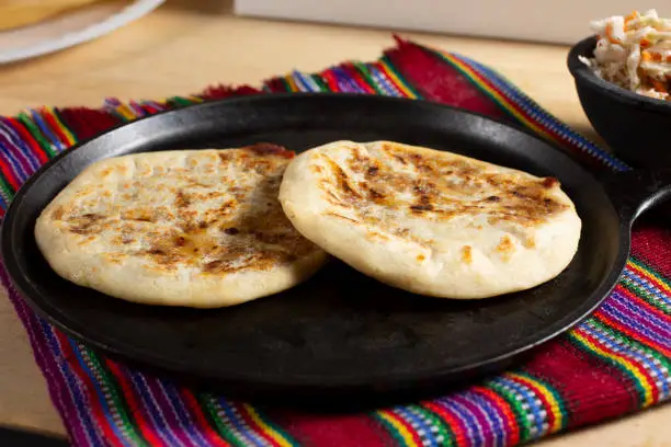 A view of pupusas on a comal, in a still life setting.