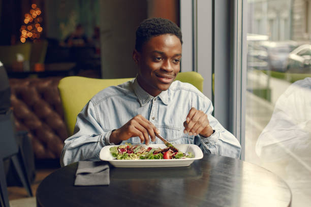 istock Black man sitting in a cafe and eating a vegetable salad 1269759204