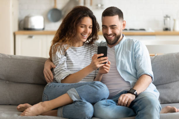 istock Close up smiling man and woman hugging using smartphone. 1269761458
