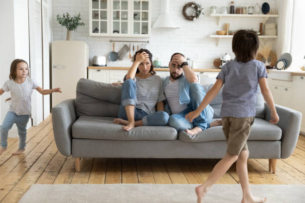 istock Hyperactive kids tired upset father and mother sitting at couch. 1269761478