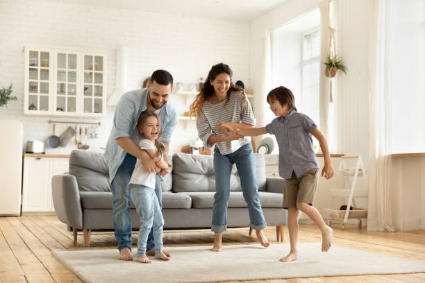 Happy family playing funny game having fun together. Happy family playing funny game having fun together with little son and daughter in modern living room. Young dad and mother with adorable cute children doing exercises, enjoying weekend at home. potential energy stock pictures, royalty-free photos & images