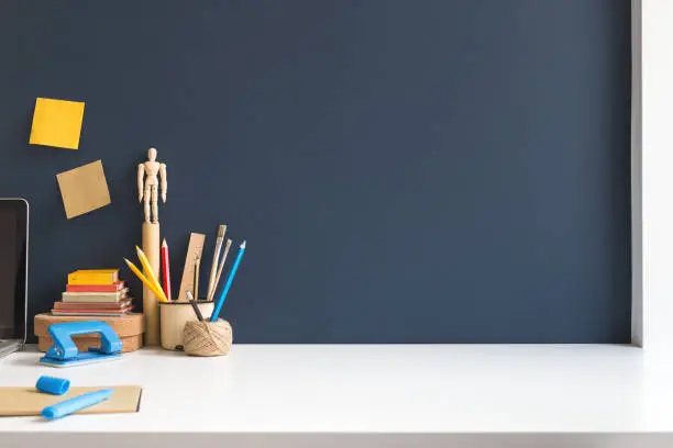 Photo of Workspace of a student with empty space on a desk. Mockup. dark blue wall.