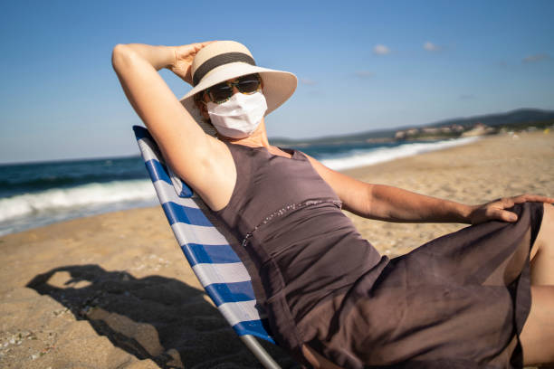 istock Vacationing Woman Wearing Face Mask on Sandy Beach 1269762350