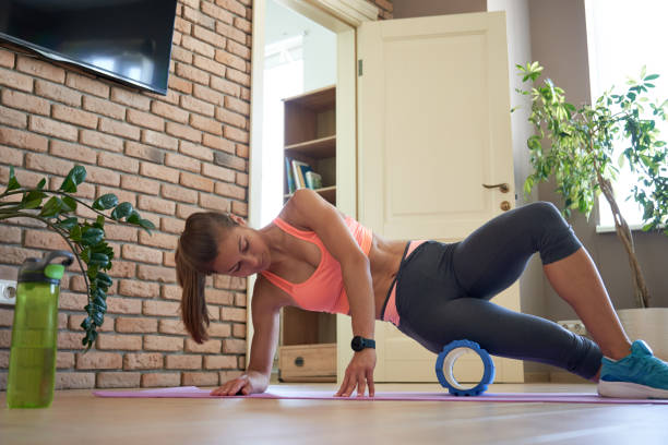 自宅で運動をしている泡マッサージローラーに転がるスポーティな女性をフィット。 - stretching yoga exercise mat women ストックフォトと画像