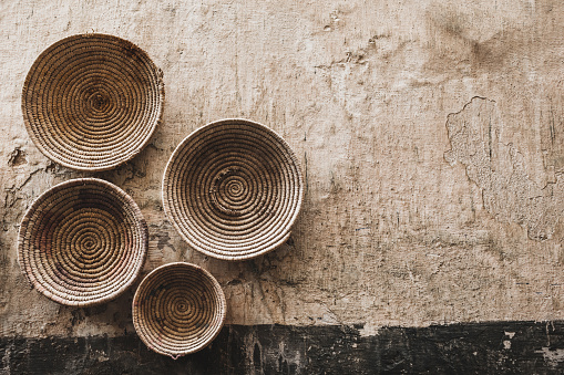 Handmade wicker round baskets hanging on textured wall in Marrakech medina souk. Traditional moroccan manufacture. Grand Bazaar.