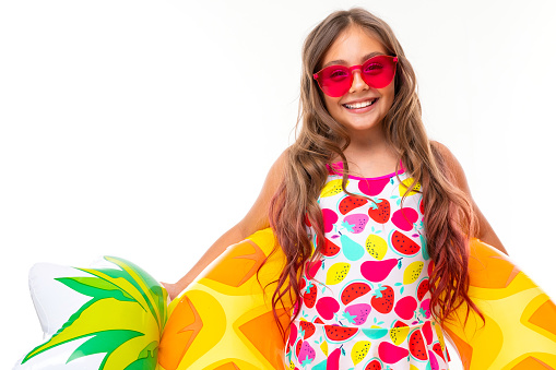 bright portrait of a girl in a swimsuit in sunglasses with a swimming circle in the form of pineapple.