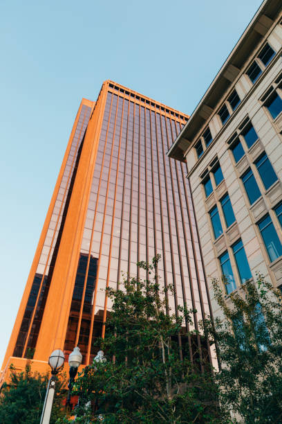Sunrise highlights glass wall of skyscraper  on Sixth Avenue in Portland, Oregon, with views of Forrest Park hill between buildings