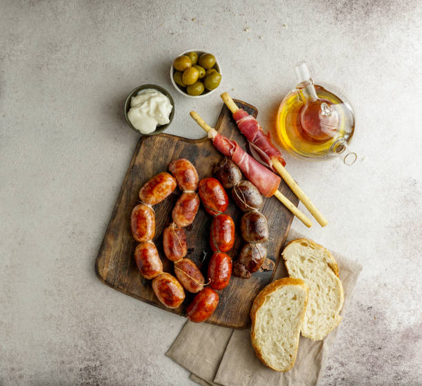 roasted spanish sausages on the cutting board - butifarra blanca, chorizo, morcilla de cebolla, jamon and garlic sause aioli roasted spanish sausages on the cutting board - butifarra blanca, chorizo, morcilla de cebolla, jamon and garlic sause aioli cebolla stock pictures, royalty-free photos & images