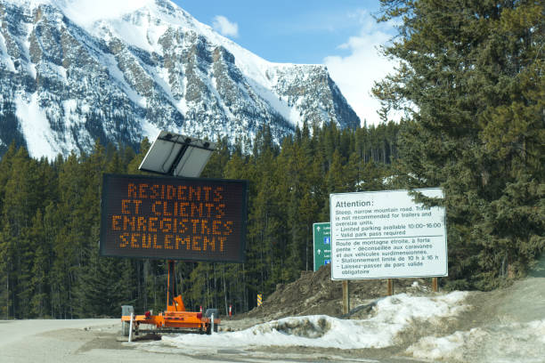 blick auf das straßenschild am eingang des dorfes louise lake, das besagt, dass nur anwohner und registrierte gäste aufgrund der situation von covid-19 durchfahren dürfen - landscape national park lake louise moraine lake stock-fotos und bilder