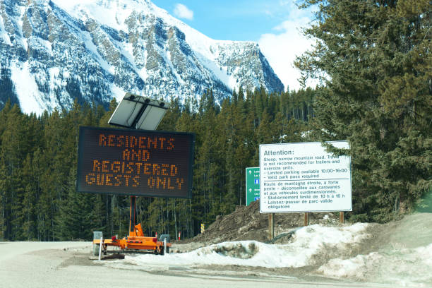 blick auf das straßenschild am eingang des dorfes louise lake, das besagt, dass nur anwohner und registrierte gäste aufgrund der situation von covid-19 durchfahren dürfen - landscape national park lake louise moraine lake stock-fotos und bilder