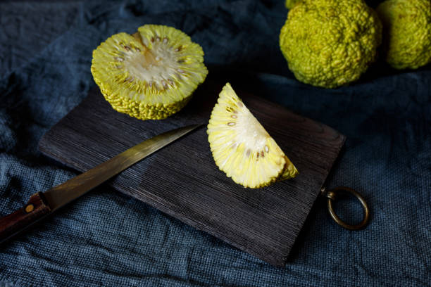 Osage Orange (Maclura pomifera) cut into pieces on an old chopping board. Maclura use in alternative medicine. Osage Orange (Maclura pomifera) cut into pieces on an old chopping board. Maclura use in alternative medicine. maclura pomifera stock pictures, royalty-free photos & images