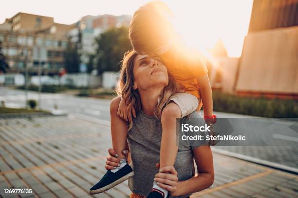 Mother And Son Playing In Public Park Driving Scateboard Stock Photo - Download Image Now