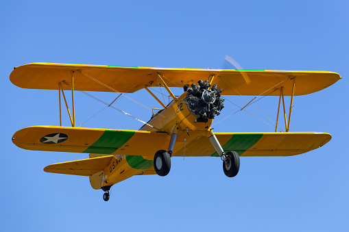Tyabb, Australia - March 9, 2014: Vintage 1941 Boeing Stearman (A75N1) biplane aircraft used by the United States military as a training aircraft during World War II taking off from Tyabb Airport.