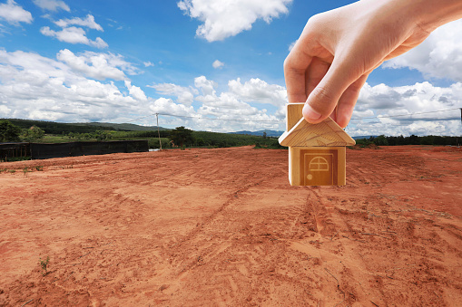 House symbol with location pin and Empty dry cracked swamp reclamation soil, land plot for housing construction project with and beautiful blue sky with fresh air Land for sales landscape concept